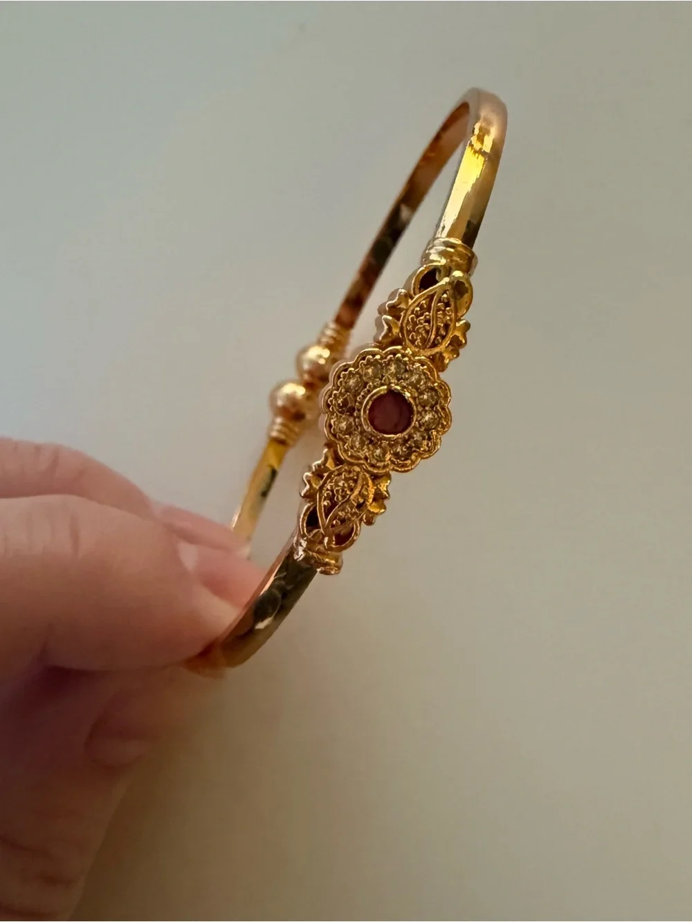 Gold bangle with red gemstone flower